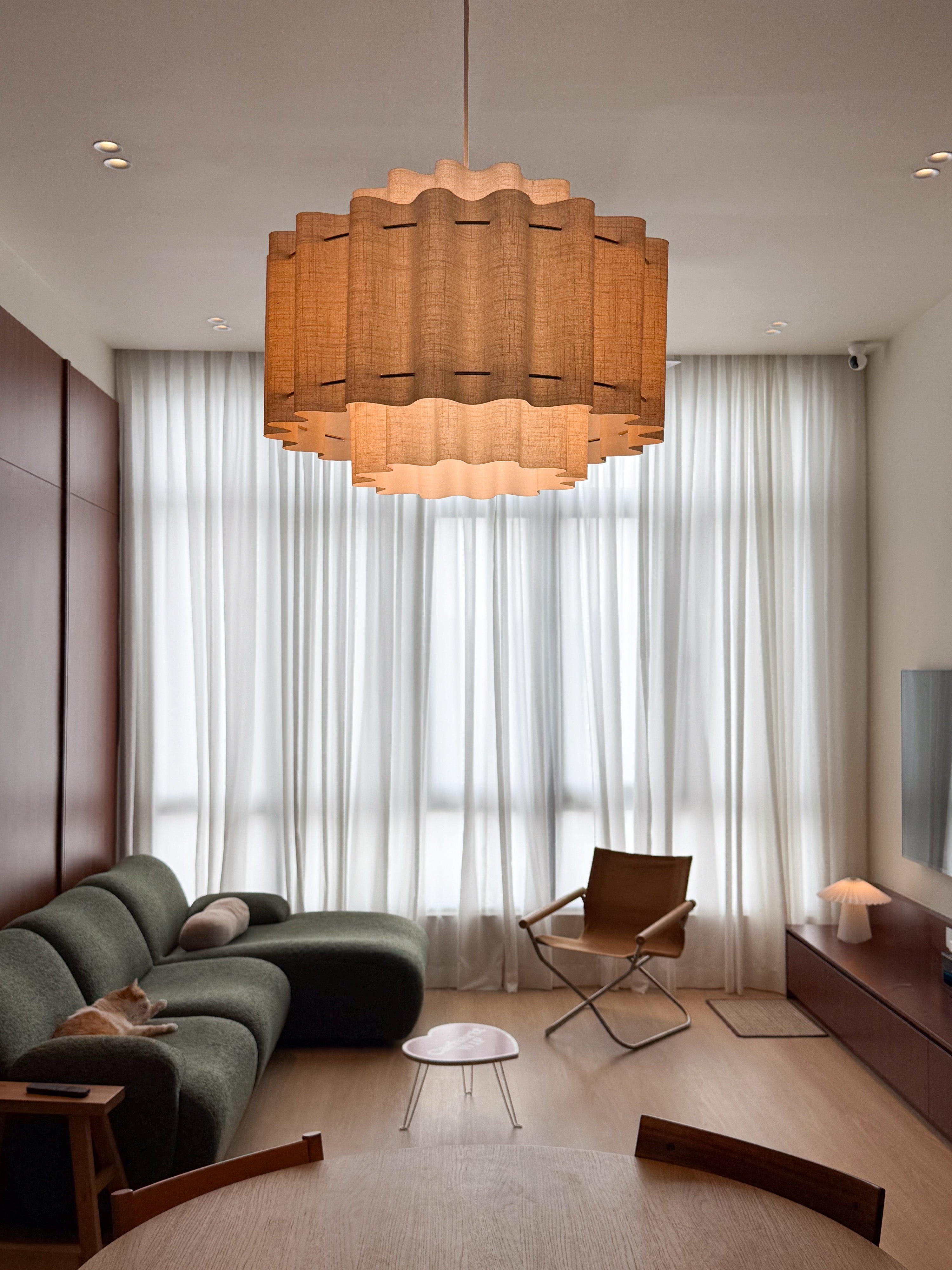 Mid-century condo living room at The Maple OUG with pleated pendant, olive green sofa and cherry wood wall, interior design by Mugo Space