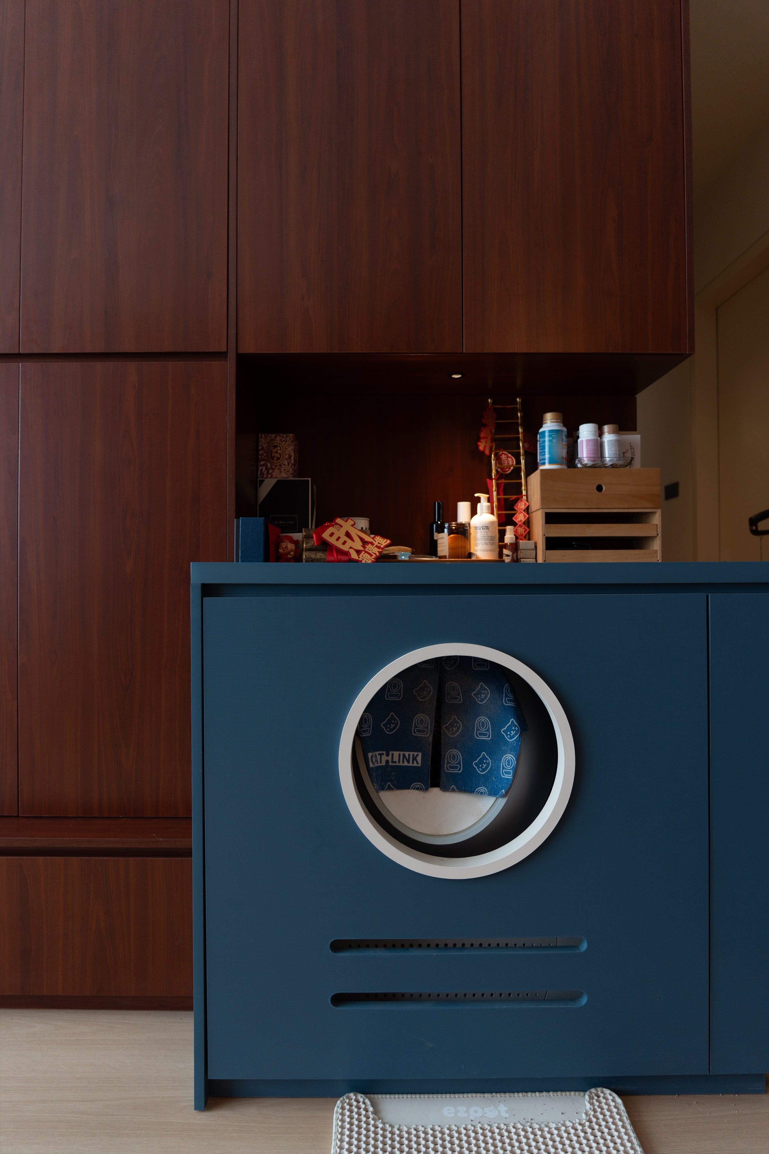 Navy cat litter cabinet with round porthole opening and ventilation slots, custom carpentry by Mugo Space