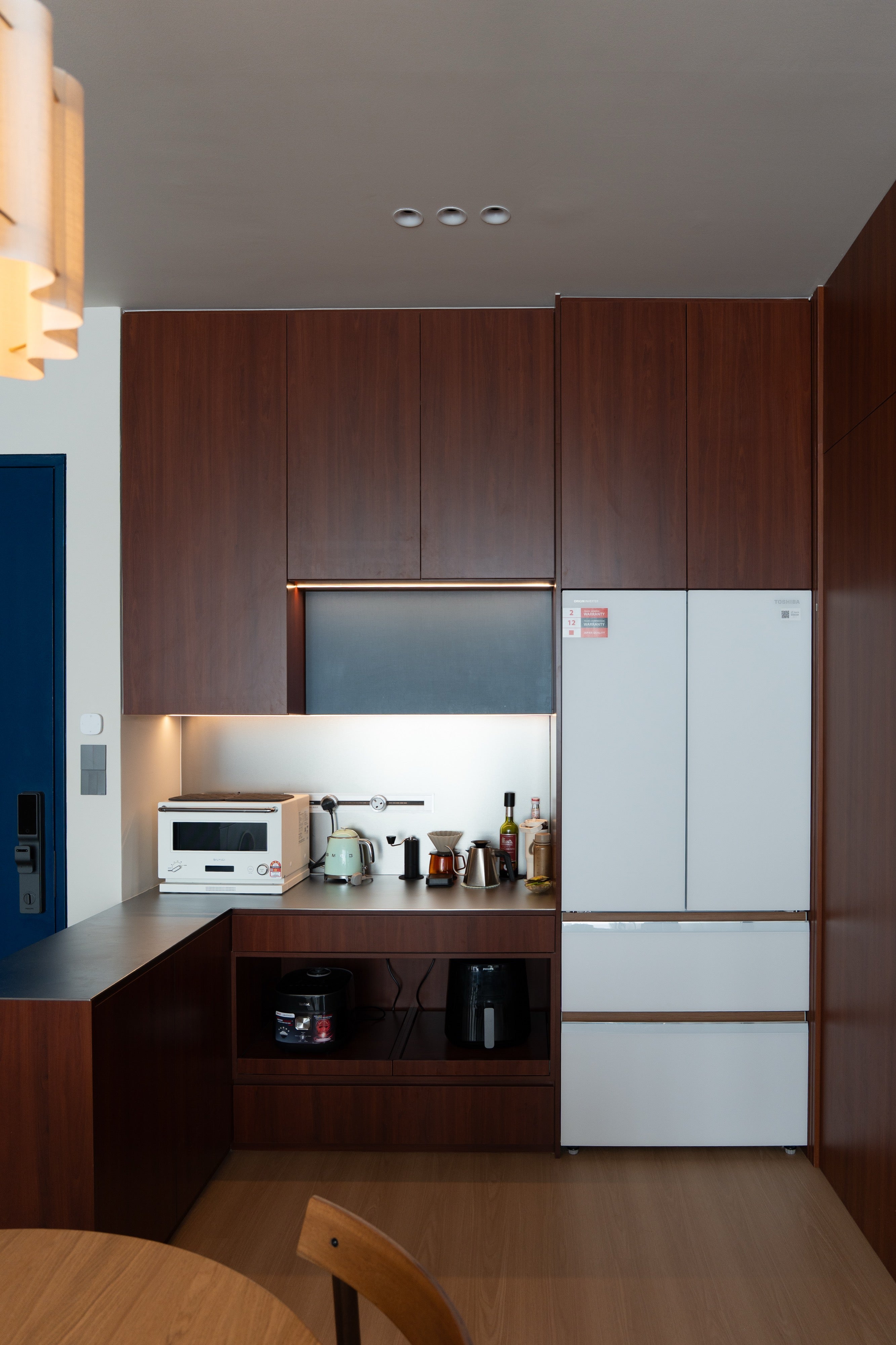 Dry pantry with cherry cabinets, dark grey backsplash and built-in fridge column