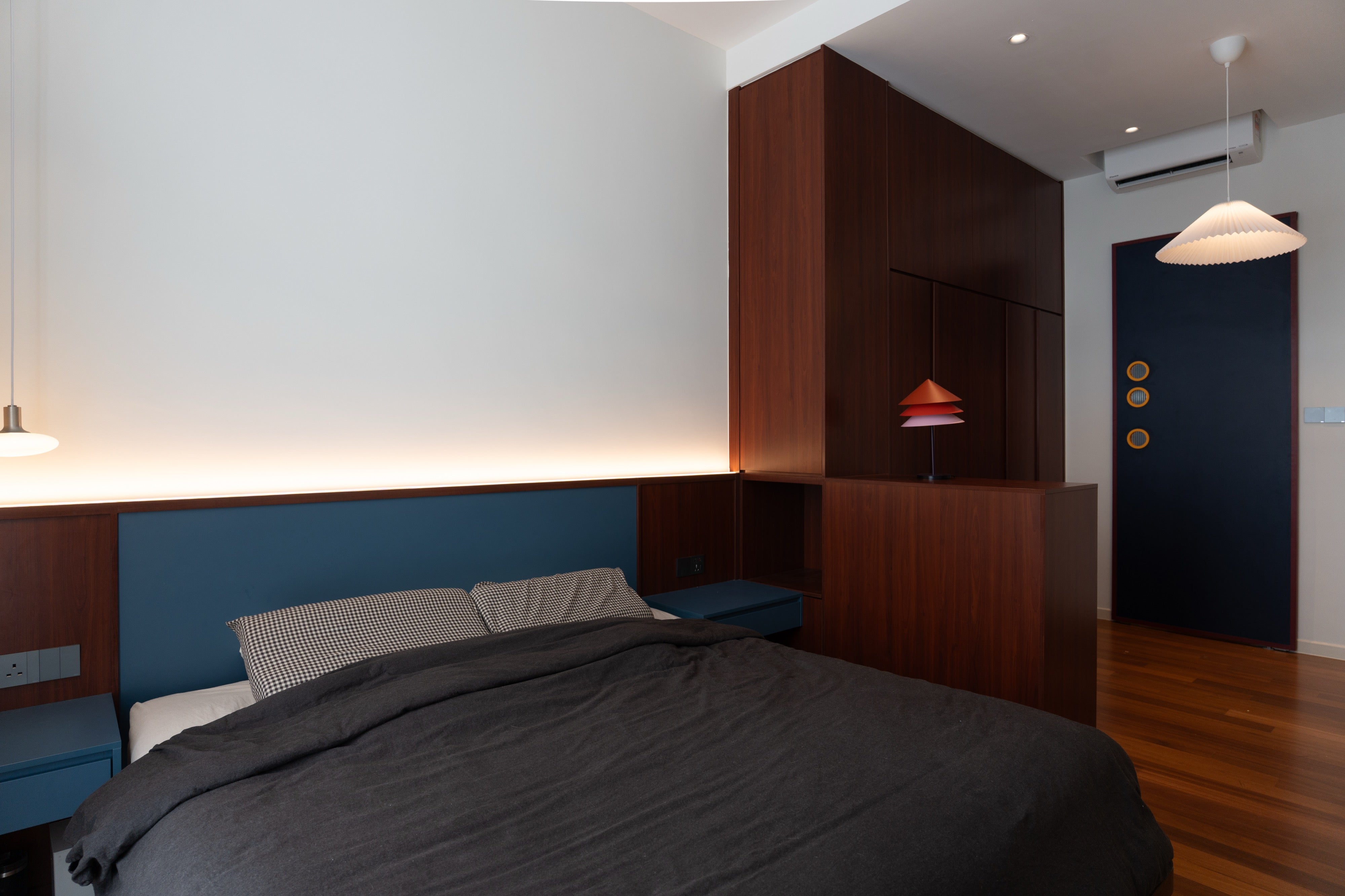 Master bedroom with navy upholstered headboard, cove light and cherry wardrobe divider