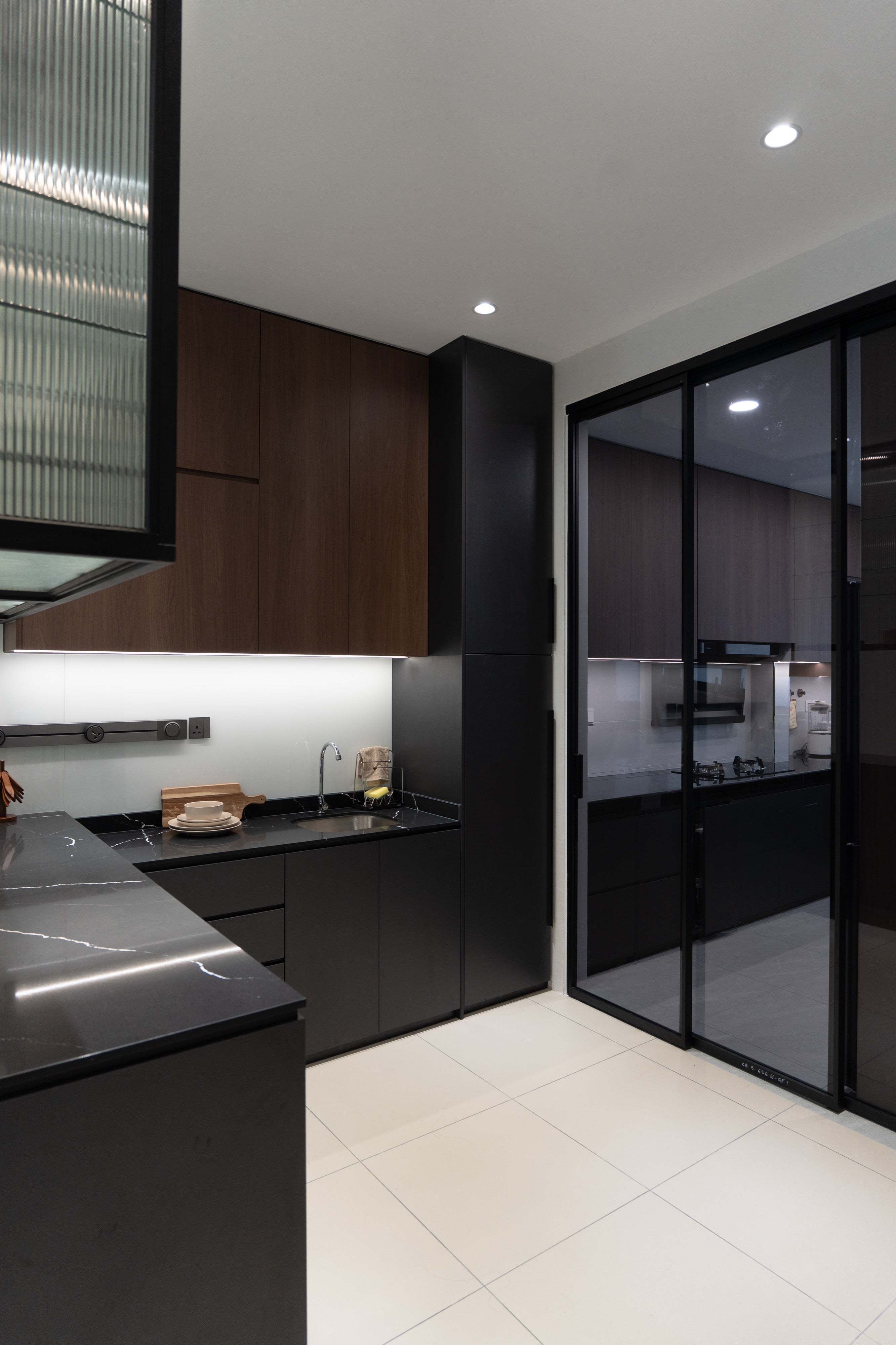 Dry kitchen with black quartz worktop and black framed sliding glass door to the wet kitchen