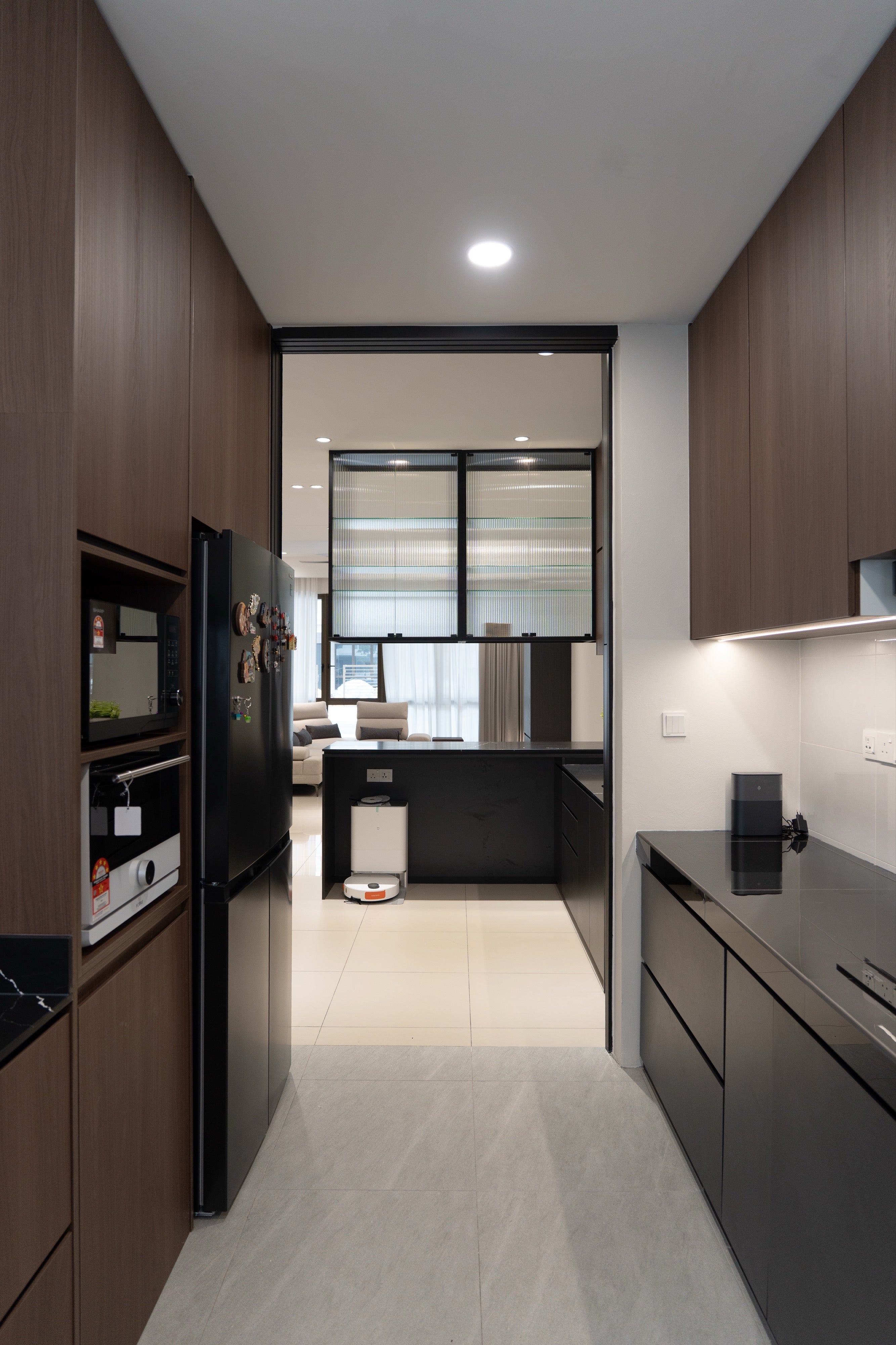 Wet kitchen with walnut and matte black cabinets looking through to the dry kitchen and living room