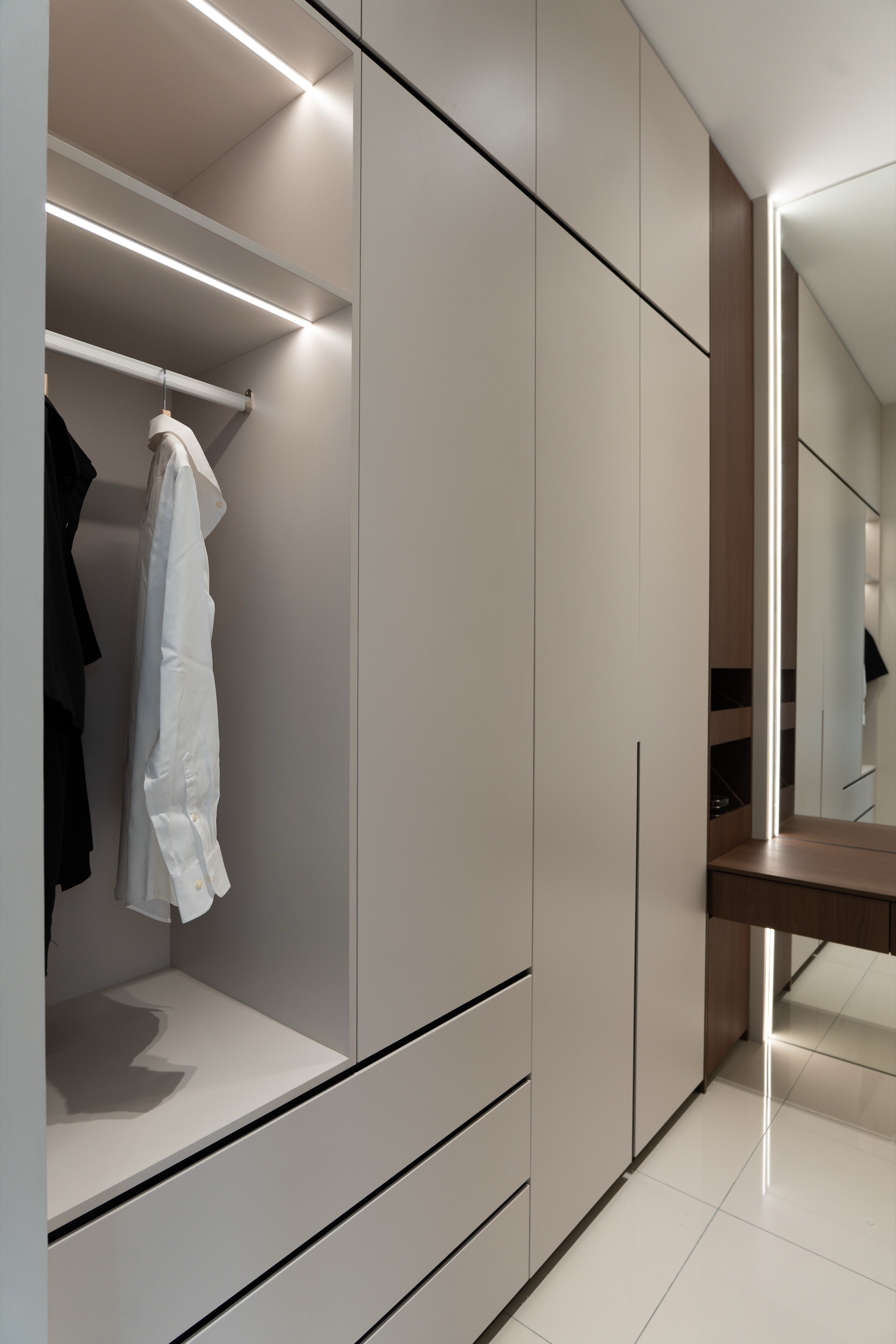 Walk-in wardrobe with open lit shelving, hanging rail and drawers, custom carpentry by Mugo Space