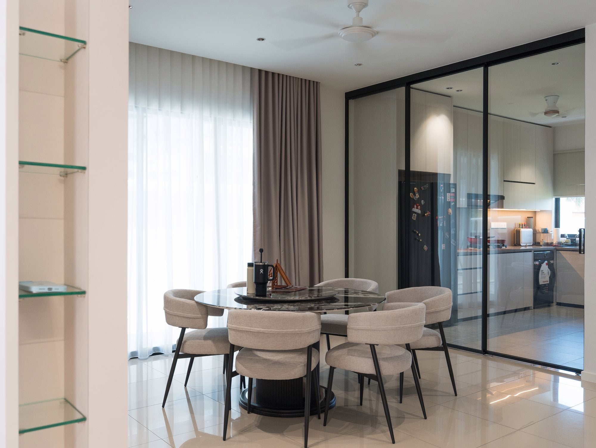 Round dining table beside the glass-partitioned wet kitchen