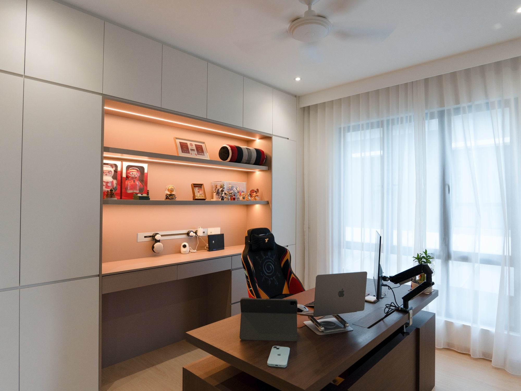 Study with long timber desk and warm-lit shelving