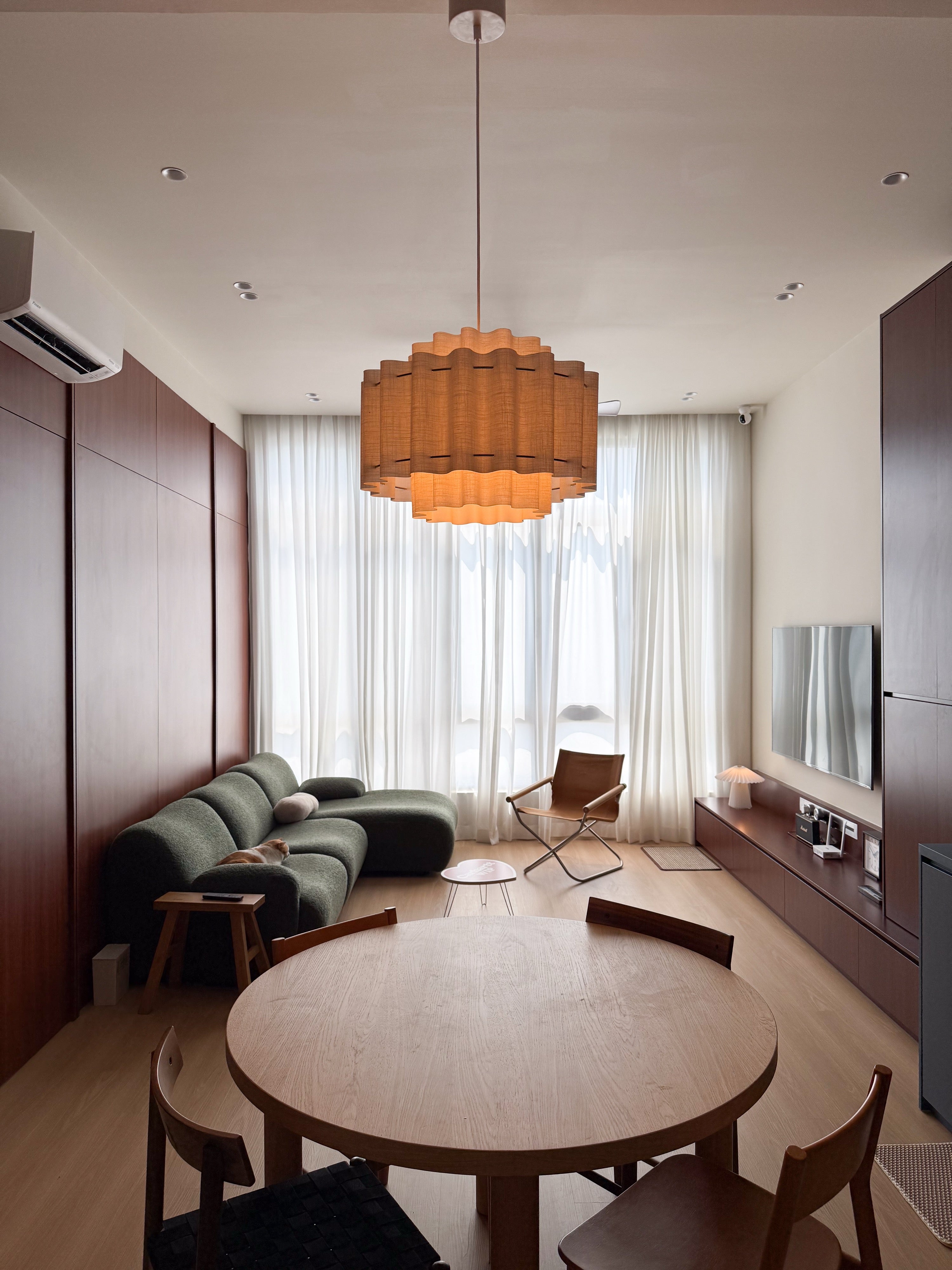 High ceiling living and dining area with pendant light and sheer curtains in an OUG condominium