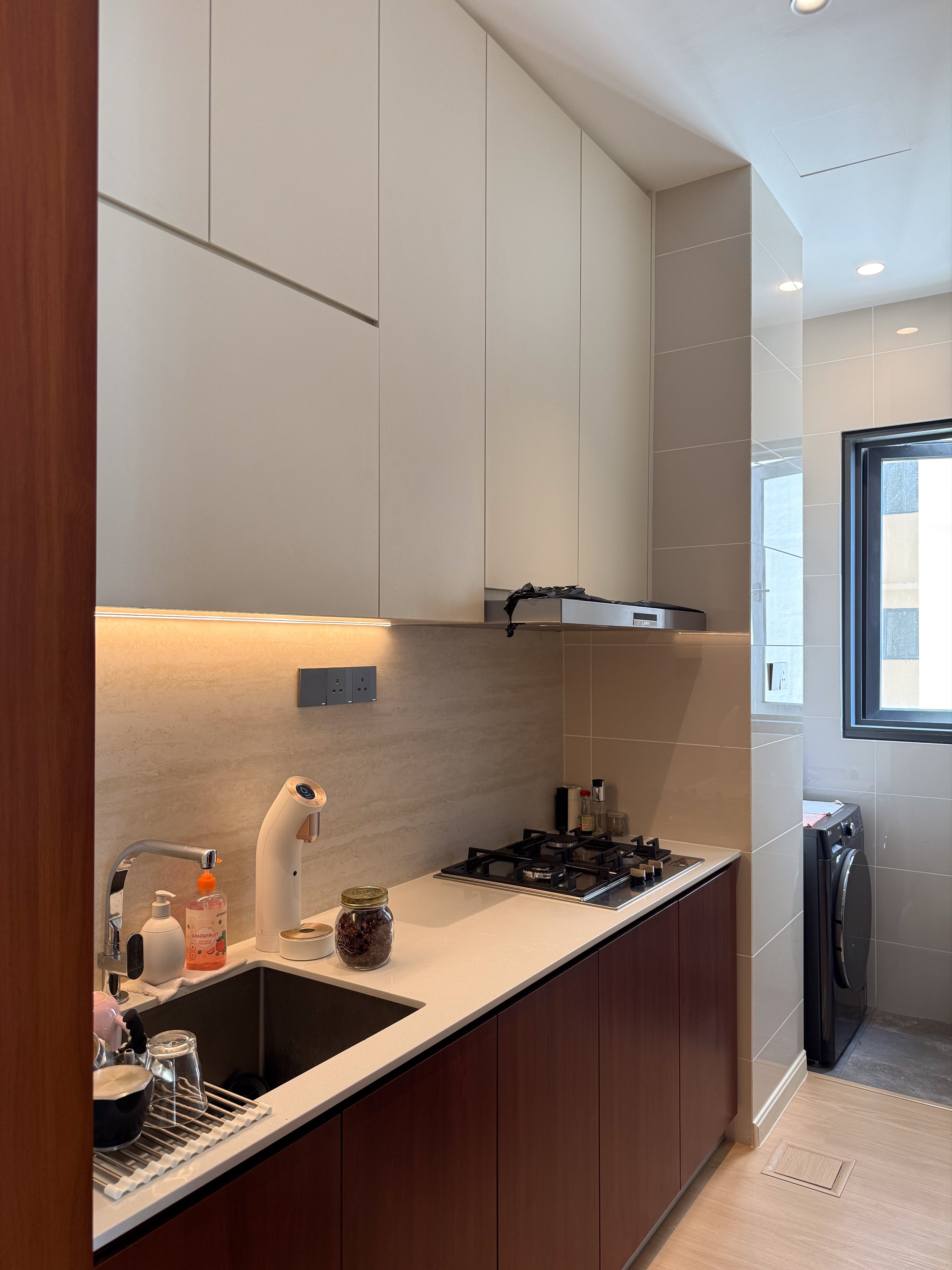 Wet kitchen with white overhead cabinets, travertine-look backsplash and cherry base cabinets